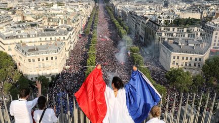 On ne sait pas comment elle s'est trouvée là. Mais, du haut de l'Arc de Triomphe, cette supportrice française domine une véritable marée humaine sur les Champs Elysées. (LUDOVIC MARIN / AFP)