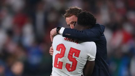 Le sélectionneur anglais Gareth Southgate avec Bukayo Saka, après la finale de l'Euro 2021 perdue contre l'Italie, dimanche 11 juillet. (LAURENCE GRIFFITHS / POOL / AFP)