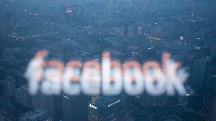 Le logo Facebook devant une ville. Photo d'illustration. (ED JONES / AFP)