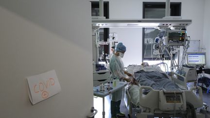 Un membre de l'équipe médicale de l'hôpital de Colmar (Haut-Rhin) prends soin d'un patient atteint du Covid-19 le 22 avril 2021. (SEBASTIEN BOZON / AFP)