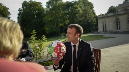 Emmanuel Macron tient un ballon offert par la Première ministre norvégienne, Erna Solberg, le 6 juillet 2018, au palais de l'Elysée, à Paris. (KAMIL ZIHNIOGLU / AFP)