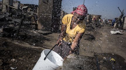 Une femme remplit un seau d'eau dans un bidonville en Afrique du Sud, le 10 octobre 2014. (MARCO LONGARI / AFP)