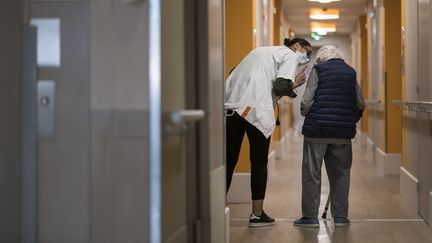 Le résident d'un Ehpad marche dans les couloirs, aidé d'une soignante, le 16 avril 2020 dans le Doubs. (SEBASTIEN BOZON / AFP)