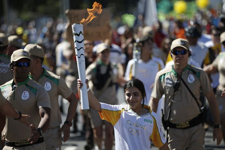 Trois mois avant l'ouverture officielle des JO de Rio il y a 5 ans, une jeune réfugiée syrienne de 12 ans, Hana Khaled Daqqah, porte la flamme olympique à travers les rues de Brasilia, le 3 mai 2016,&nbsp; (RIO2016/ANDRE MOURAO / AFP)