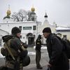 Un membre des forces de sécurité ukrainiennes discute avec un visiteur de la laure des Grottes de Kiev, le 22 novembre 2022. (SERGEI CHUZAVKOV / AFP)