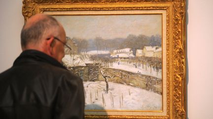 Un homme regarde le tableau d'Alfred Sisley, "Effet de neige à Louveciennes", en septembre 2011,&nbsp;au&nbsp;musée Von der Heydt, à Wuppertal, en Allemagne. (PATRIK STOLLARZ / AFP)