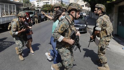 Des soldats libanais protègent des enseignants fuyant leur école après des tirs lors d'une manifestation&nbsp;contre le juge chargé de l'enquête sur l'explosion au port de Beyrouth, le 14 octobre 2021 à Beyrouth (Liban).&nbsp; (HUSSEIN MALLA / AP / SIPA)