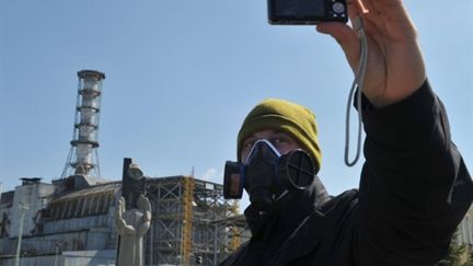 Un visiteur prend une photo, le 18/04/2011, du réacteur n°4 de Tchernobyl à l'origine de la catastrophe nucléaire. (AFP)