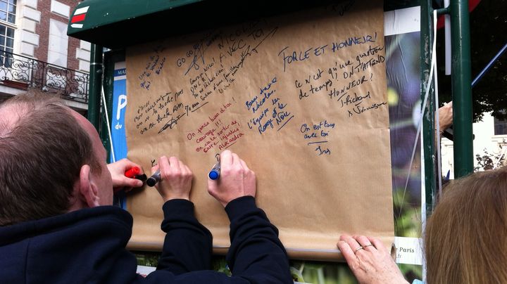 Des participants &agrave; la manifestation de soutien &agrave; Nicolas,&nbsp;l'opposant au mariage des homosexuels condamn&eacute; &agrave; deux mois de prison ferme, lui &eacute;crivent des messages de soutien, le 23 juin 2013 &agrave; Paris. (BENOIT ZAGDOUN / FRANCETV INFO)