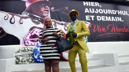 Des membres du mouvement La SAPE (Société des Ambianceurs et des Personnes Elégantes) posent devant une affiche du roi de la rumba congolaise Papa Wemba, lors d'une journée d'hommage à l'artiste le 24 avril 2017 à Abidjan. (SIA KAMBOU / AFP)