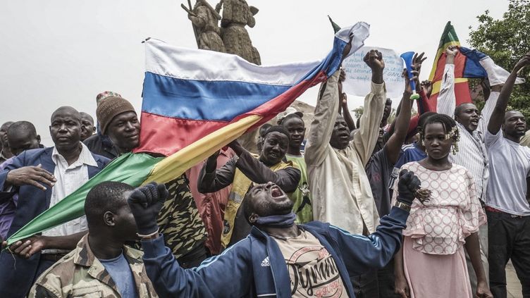 Des manifestants brandissent des drapeaux russes et maliens à Bamako, lors d'une manifestation contre l'influence française dans le pays, le 27 mai 2021. (MICHELE CATTANI / AFP)