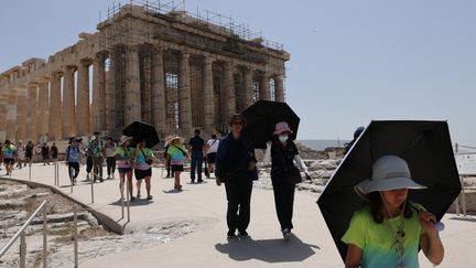 Des touristes visitent le temple du Parthénon, au sommet de la colline de l'Acropole, à Athènes (Grèce), le 23 juillet 2023. (COSTAS BALTAS / ANADOLU AGENCY / AFP)