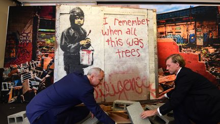 La peinture murale de Banksy "I remember when all this was trees", mise en scène par Martin Nolan (à gauche) et Michael Doyle, de la maison d'enchères Julien, en vue de sa vente à Los Angeles (23 septembre 2015)
 (Frédéric J. Brown / AFP)