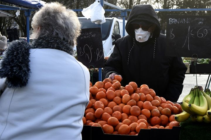 Un marchand de fruits et légumes porte un masque sur le marché de Crépy-en-Valois (Oise), le 1er mars 2020. (FRANCOIS LO PRESTI / AFP)