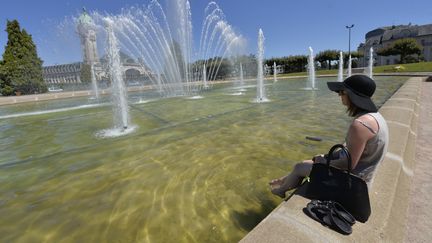 Une femme est assise sur le bord d'un bassin à Limoges (Haute-Vienne), le 19 juillet 2016. (PASCAL LACHENAUD / AFP)