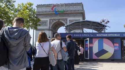 Des gens font la queue pour acheter des produits olympiques près de l'Arc de Triomphe avec le logo des Jeux Paralympiques à Paris, le 17 septembre 2024. (LUIS BOZA / NURPHOTO / AFP)