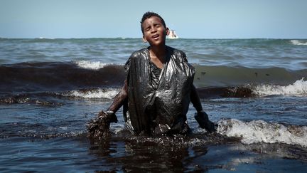 Everton Miguel dos Anjos&nbsp;sort de l'eau souillé de pétrole, lundi 21 octobre, à Cabo de Santo Agostinho, dans l'Etat du Pernambouc au Brésil. (LEO MALAFAIA / AFP)