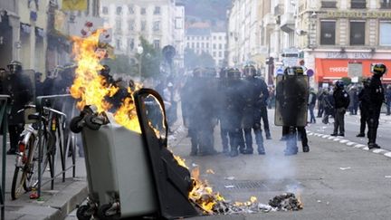 Policiers attendant près d'une poubelle en feu, à la suite des incidents qui ont éclaté à Lyon le 19 octobre 2010 (AFP - PHILIPPE DESMAZES)