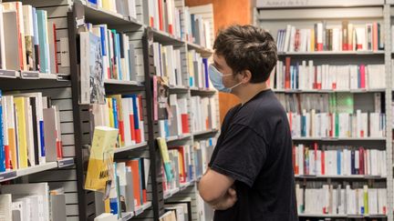 &nbsp;Un jeune homme masqué regarde les rayons de livres d'une librairie de Lorient en août 2020. (MAUD DUPUY / HANS LUCAS)