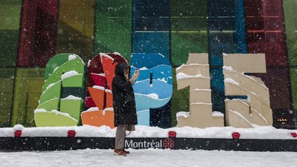 Une personne prend un selfie devant un panneau de la COP15 de Montréal, au Canada, le 17 décembre 2022. (ANDREJ IVANOV / AFP)