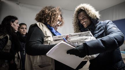 Une travailleuse sociale donne des vêtements à un homme dans un centre pour migrants et réfugiés, à Paris, le 10 novembre 2016. (PHILIPPE LOPEZ / AFP)