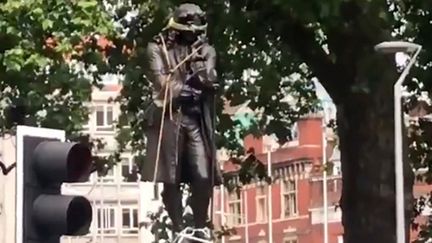 Une capture d'écran d'une vidéo diffusée sur le compte Twitter de&nbsp;William Want (@willwantwrites)&nbsp;qui montre la statue d'Edward Colston en train d'être déboulonnée à Bristol (Royaume-Uni), le 7 juin 2020. (WILLIAM WANT / TWITTER / AFP)