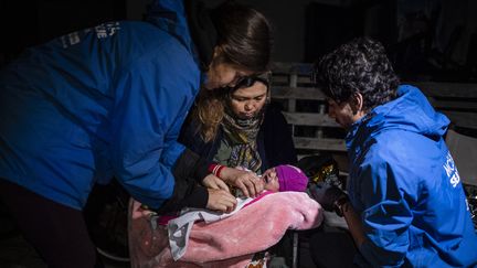 Des volotaires aident une migrante afghane, sur l'île de Lesbos, en Grèce, le 29 septembre 2019. (ANGELOS TZORTZINIS / AFP)