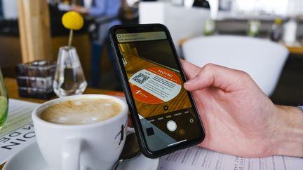 Le client d'un café scanne un QR code à&nbsp;Sankt Peter-Ording (Allemagne), le 1er mai 2021. (FRANK MOLTER / DPA / AFP)