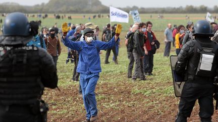 Un manifestant contre le projet d'une réserve d'eau agricole devant deux gendarmes à Sainte-Soline, dans les Deux-Sèvres le 29 octobre 2022. (BENOIT FELACE / MAXPPP)