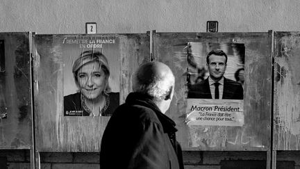 Un homme regarde les affiches électorales, devant un bureau de vote à Lyon, le 21 avril 2017. (JEFF PACHOUD / AFP)