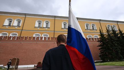 Un homme tient un drapeau russe à proximité du Kremlin, à Moscou (Russie), le 24 juin 2023. (NATALIA KOLESNIKOVA / AFP)