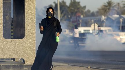 Une manifestante s'enfuit alors que la police envoie du gaz lacrymog&egrave;ne &agrave; Diah (Bahre&iuml;n), le 28 janvier 2012. (CAREN FIROUZ / REUTERS)