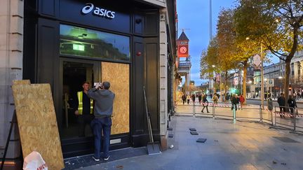 Asics store whose broken windows are replaced by wooden panels.  (RICHARD PLACE / RADIOFRANCE)