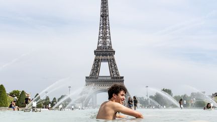 Un jeune homme se baigne dans une fontaine au pied de la tour Eiffel au Trocadéro, le 24 juin 2019 à Paris. (SAMUEL BOIVIN / NURPHOTO)