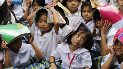 Des &eacute;coli&egrave;res se prot&egrave;gent la t&ecirc;te avec des cahiers lors d'un exercice de simulation de tremblement de terre &agrave; Manille (Philippines), le 4 septembre 2012. (ROMEO RANOCO / REUTERS)