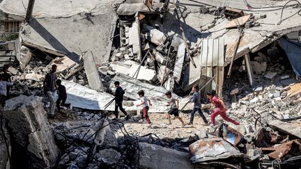 Des enfants courent devant les décombres d'un bâtiment effondré à Rafah, dans le sud de la bande de Gaza, le 9 avril 2024. (AFP)