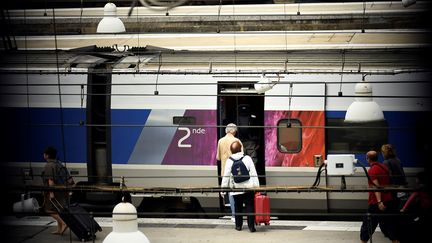 Des voyageurs embarquent dans un train à la gare Montparnasse, mardi 1er août 2017.&nbsp;Le trafic ferroviaire y est perturbé depuis dimanche en raison d'une panne de signalisation. (LIONEL BONAVENTURE / AFP)