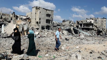 Des Palestiniens au milieu des d&eacute;bris d'immeubles d&eacute;truits par les bombardements isra&eacute;liens, samedi 26 juillet 2014. (ALI HASSAN / ANADOLU AGENCY / AFP)