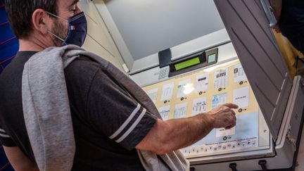 Un homme vote aux élections régionales sur une machine à voter, le 20 juin 2021, à Theix-Noyalo (Morbihan). (BAPTISTE ROMAN / HANS LUCAS)