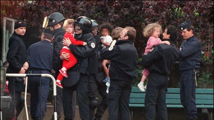 Des policiers évacuent les derniers enfants otages de la maternelle Commandant Charcot, le 15 mai 1993 à Neuilly-sur-Seine. (PIERRE BOUSSEL / AFP)