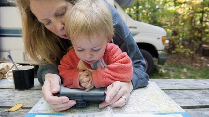 Sur la route des vacances, une mère de famille prépare l'itinéraire en même temps qu'elle petit-déjeune et distraie son enfants (illustration). (JEROME GORIN / MAXPPP)