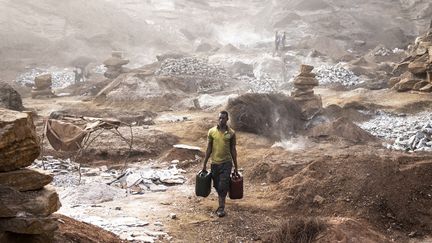 Le 29 janvier 2022, un homme transporte des jerricans d'eau&nbsp;dans la mine de granite à ciel ouvert de Pissy, une autre mine du Burkina Faso où les conditions de travail sont particulièrement difficiles. (JOHN WESSELS / AFP)