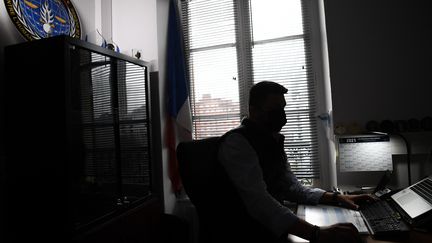 Un gendarme français de l'Office central de lutte contre les crimes contre l'humanité, les génocides et les crimes de guerre (OCLCH), travaille dans son bureau, le 21 janvier 2021 à Paris. (ALAIN JOCARD / AFP)