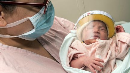 Une femme tient son nouvea-né équipé d'une visière de protection, le 28 avril 2020, à l'hôpital Mexico de San Jose (Costa Rica). (AFP)