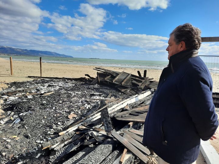 Dario Melillo, le propriétaire de L’Ultima spiaggia devant le bois qui brûle encore. (BRUCE DE GALZAIN / RADIO FRANCE)