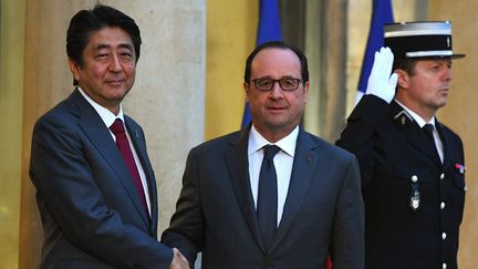 Le président français François Hollande serre la main de l'ancien Premier ministre japonais Shinzo Abe, le 20 mars 2017, au palais de l'Élysée à Paris. (GABRIEL BOUYS / AFP)