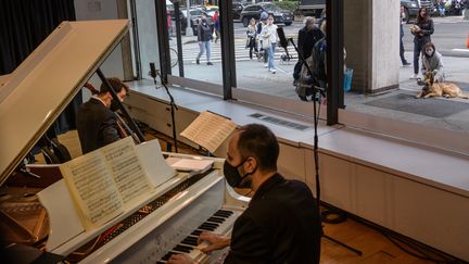 Les musiciens Michael Katz et Spencer Myer se&nbsp; produisent dans le cadre de concerts derrière une vitrine organisés par the Kaufman Music Center's, le 25 mars 2021 à New York (ANGELA WEISS / AFP)