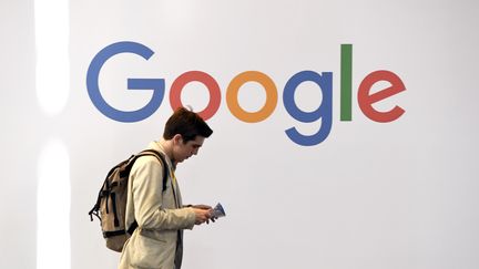 Un homme marche devant un logo de Google à VivaTech, à Paris, le 24 mai 2018. (ALAIN JOCARD / AFP)