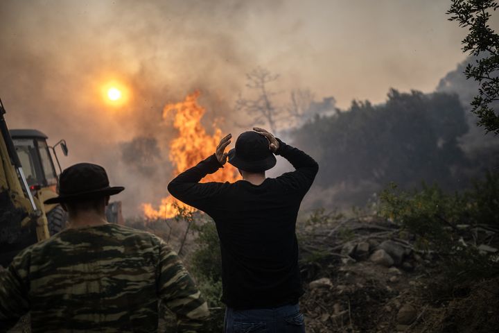 Des témoins impuissants assistent à la destruction par les flammes du village de Gennadi, sur l'île de Rhodes (Grèce), le 25 juillet 2023. (ANGELOS TZORTZINIS / AFP)