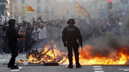 Des policiers regardent des poubelles incendi&eacute;es par des manifestants, lors d'une manifestation contre l'aust&eacute;rit&eacute;, le 29 mars 2012, &agrave; Barcelone (Espagne).&nbsp; (GUSTAU NACARINO / REUTERS)